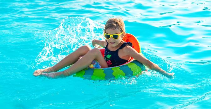 A child in a circle swims in the pool. Selective focus. Kid.