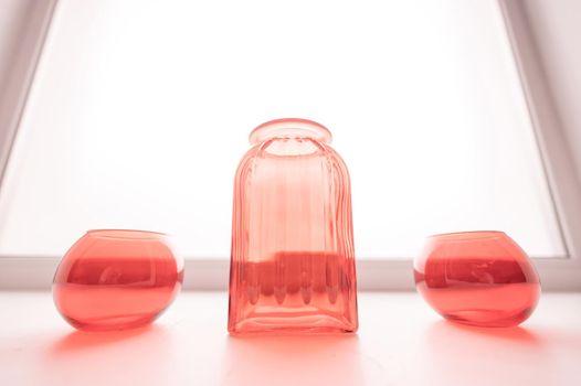 Three empty glass red vases on the windowsill