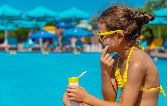 Sunscreen near the pool on the face of the child. Selective focus. Kid.