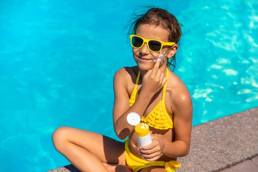 Sunscreen near the pool on the face of the child. Selective focus. Kid.
