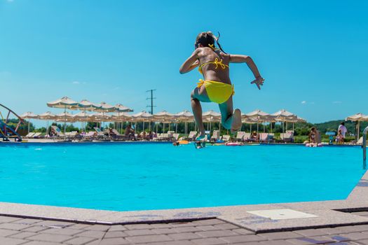 The child jumps into the pool. Selective focus. Kid.