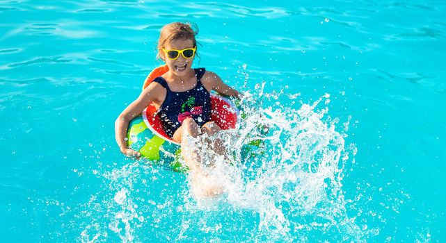 A child in a circle swims in the pool. Selective focus. Kid.