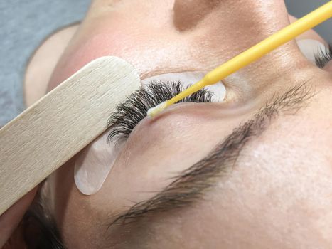 Close-up of the eyelash extension removal procedure. Portrait of a woman in a beauty salon.