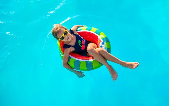 A child in a circle swims in the pool. Selective focus. Kid.
