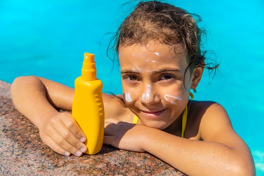 Sunscreen near the pool on the face of the child. Selective focus. Kid.