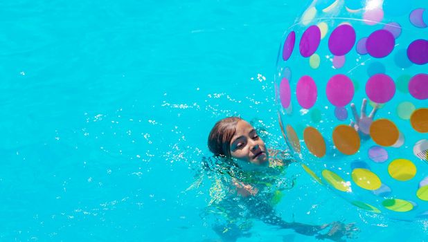 The child plays with a ball in the pool. Selective focus. Kid.