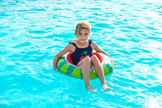 A child in a circle swims in the pool. Selective focus. Kid.