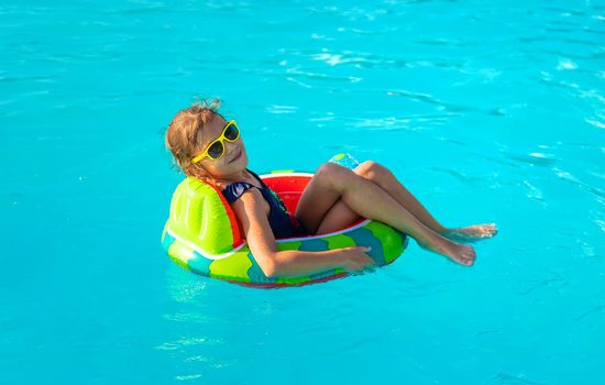 A child in a circle swims in the pool. Selective focus. Kid.
