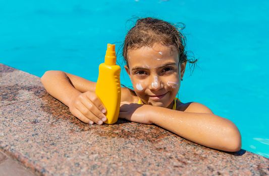 Sunscreen near the pool on the face of the child. Selective focus. Kid.