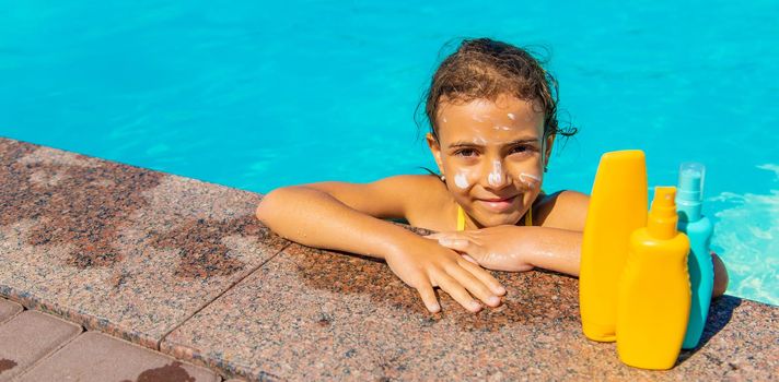 Sunscreen near the pool on the face of the child. Selective focus. Kid.