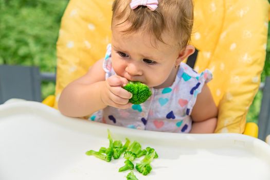 Baby eats pieces of broccoli vegetables. Selective focus. Child.