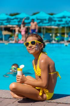 Sunscreen near the pool on the face of the child. Selective focus. Kid.