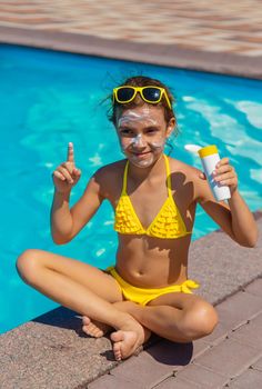 Sunscreen near the pool on the face of the child. Selective focus. Kid.