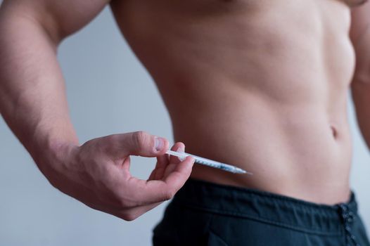 Close-up of a male torso. A shirtless bodybuilder puts himself an injection of insulin. Faceless athlete takes testosterone