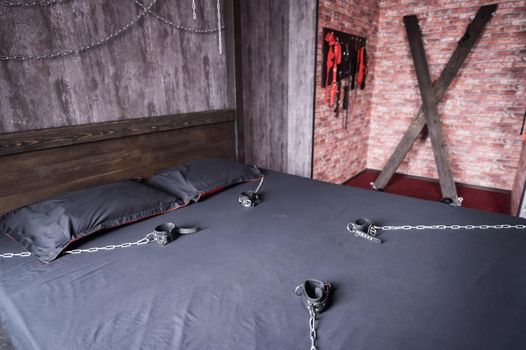 BDSM Leather handcuffs for role-playing games on a gray sheet. Bondage for carnal pleasures. Domination and submission