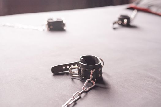 BDSM Leather handcuffs for role-playing games on a gray sheet. Bondage for carnal pleasures. Domination and submission