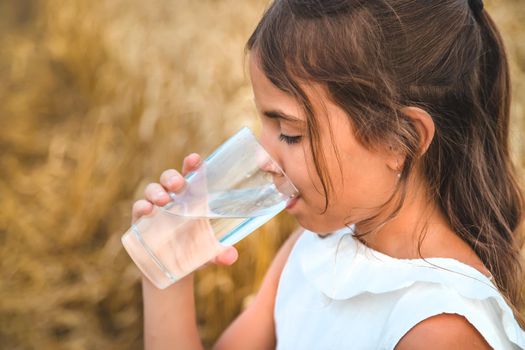 The child drinks water from a glass. Selective focus. Kid.