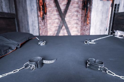 BDSM Leather handcuffs for role-playing games on a gray sheet. Bondage for carnal pleasures. Domination and submission