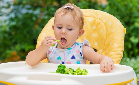 Baby eats pieces of broccoli vegetables. Selective focus. Child.