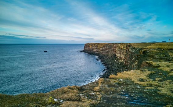 Wide angle of volcanic steep cliffs with red seams in Iceland