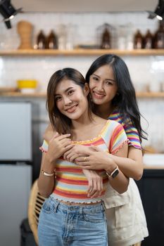 Smiling young asian lesbian couple standing affectionately together at home.