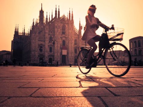 Woman cycling in Milan at sunset.
