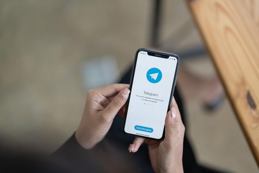 CHIANG MAI, THAILAND, JUNE 31, 2022 : Woman hand holding iPhone X with social networking service Telegram on the screen. iPhone 10 was created and developed by the Apple inc