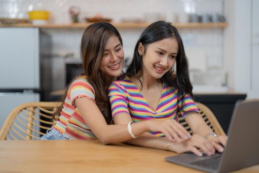 Lesbian couple sitting in living room together and using laptop computer