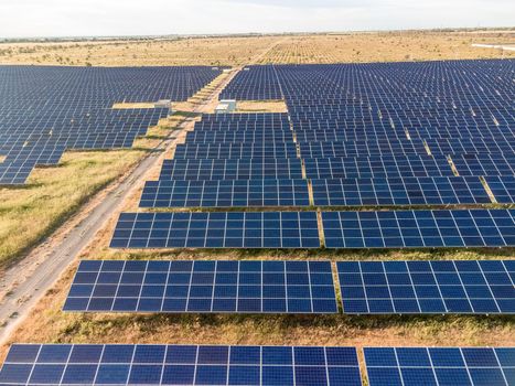 Aerial top view of a solar panels power plant. Photovoltaic solar panels at sunrise and sunset in countryside from above. Modern technology, climate care, earth saving, renewable energy concept