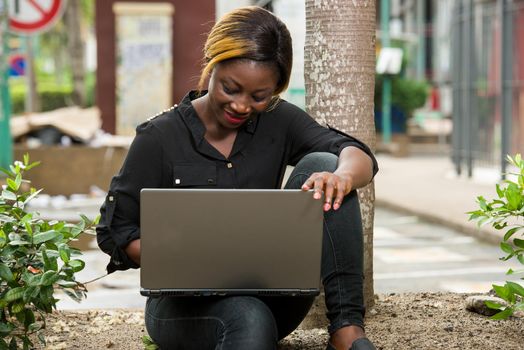 student sitting in black shirt looking at laptop smiling.