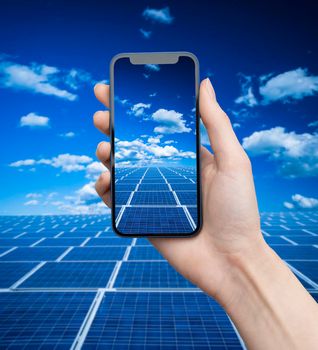 Hand holds phone over solar panels.