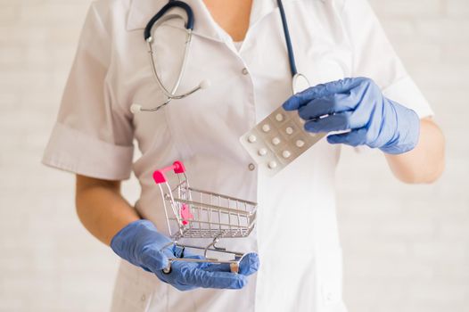 A faceless doctor puts a blister of pills in a mini shopping cart
