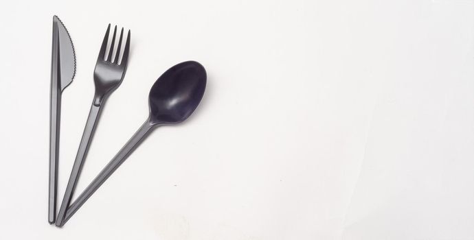 black plastic disposable knife,spoon on white background.Top view, copyspace.