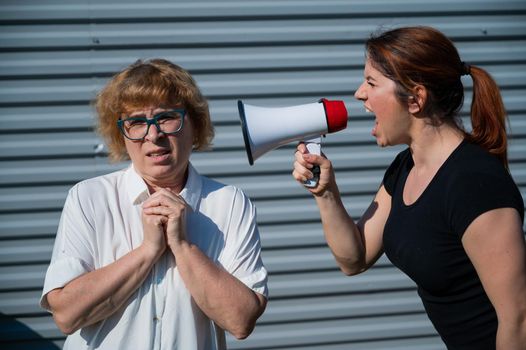 The conflict of generations. An angry middle-aged woman yells at an elderly mother through a megaphone. An adult daughter screams at an unhappy pensioner over a loudspeaker. Quarrel in the family