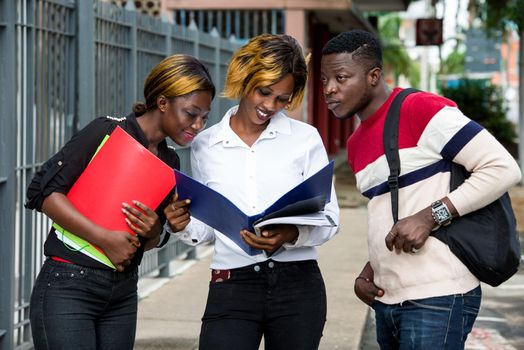 group of students standing outside after class look at notebook smiling.