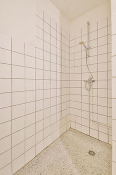 Shower faucets attached to tiled wall near glass partition and ornamental curtail in washroom at home