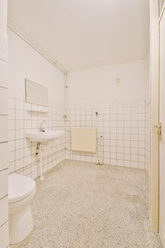 Modern flush toilet and ceramic sink installed on white tiled walls near mirror and towel in small restroom at home