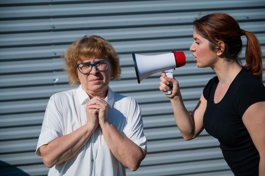 The conflict of generations. An angry middle-aged woman yells at an elderly mother through a megaphone. An adult daughter screams at an unhappy pensioner over a loudspeaker. Quarrel in the family