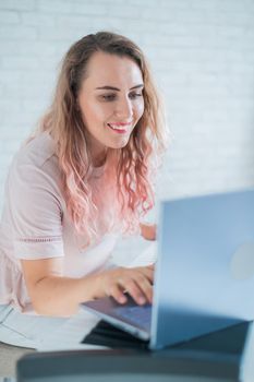 A friendly woman plays the electronic piano and conducts a video blog on her laptop. Stay home. Musical instrument teacher. Distance learning music quarantined