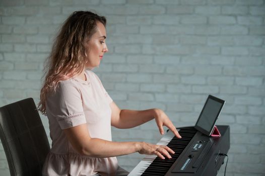 Caucasian woman remotely learns to play the piano by video communication on a digital tablet.