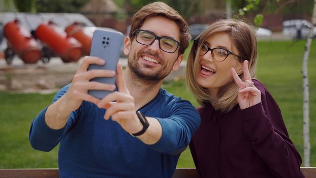 Friends woman and man close up ,wearing glasses take selfie with phone, feel happy smiling. Social networking outdoors. Friendship portrait concept.