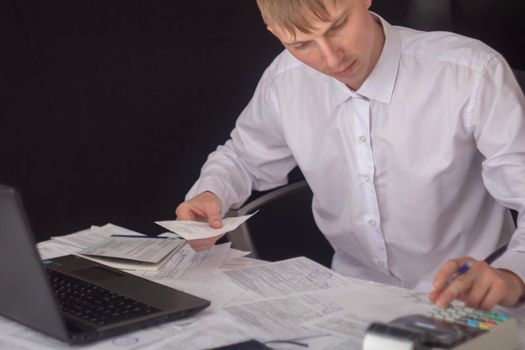 A businessman works with stocks, bonds, obligations, securities and documents in a night office. Fulfillment of obligations to work with documents in the office. Employee at a laptop in the office.