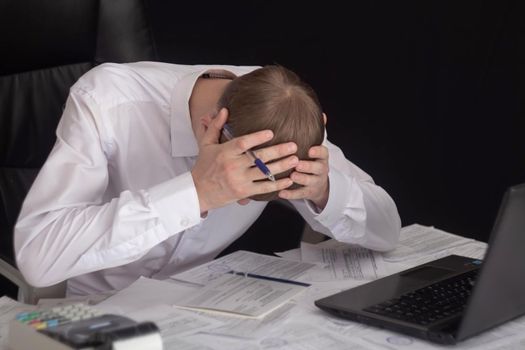 The state of crisis, failure and depression. Work with documents. Frustrated guy at the Desk with documents. Problems with documents, debts on loans and tax operations. Confiscation