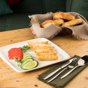 A dining table full of delicious salad on a white plate next to basket of bread