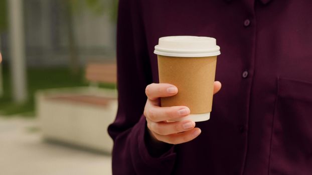 Close up hand of a business woman holding coffee and talking with somebady. Cup detail.