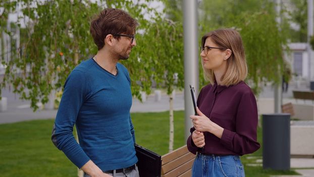 Man and Woman talking Outdoor City Park Business problems resolve ambiguities Young managers wearing casual clothes Caucasian successful employees.