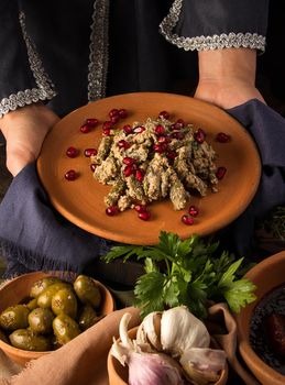 A vertical shot of a waitress presenting a kuchmachi and tomahawk steak in the background