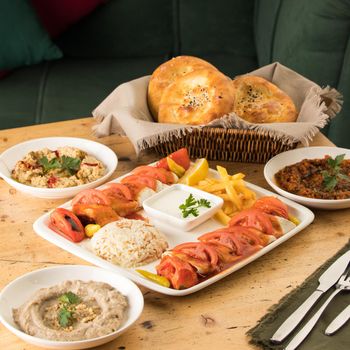 A dining table full of delicious dishes and a basket of bread