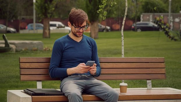 Portrait focused man writing using mobile phone outdoor.