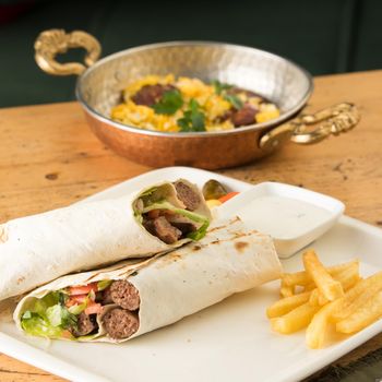 A closeup shot of kebabs with vegetables wrapped in a tortilla